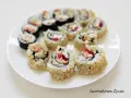 Talerz sushi z hosomaki takuan, łososiem i warzywami. Roladki ryżowe w sezamie i nori.