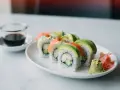 Uramaki california z awokado, krabem i ogórkiem, podane z wasabi i imbirem.