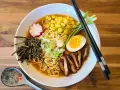 A miska pełna aromatycznego ramen miso z makaronem, jajkiem na pół, kukurydzą, grzybami shiitake, nori i szczypiorkiem.