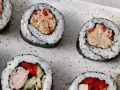 Kilka kawałków sushi z tuńczykiem i warzywami na talerzu.