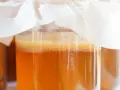 Słoiki z kombuchą, widoczna kultura SCOBY i bąbelki.
