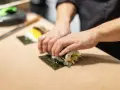 Dłonie zwijają sushi na arkuszu nori, ukazując jego wszechstronne właściwości kulinarne.
