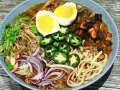 A miseczce ramen z wieprzowiną, jajkiem na pół, papryczkami jalapeño, cebulą i kolendrą.