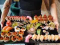 Taca pełna różnorodnego sushi: rolki z łososiem, tuńczykiem, krewetkami, a także nigiri. To właśnie sushi!