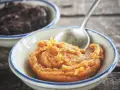Pomarańczowa pasta miso w miseczce, obok ciemniejsza pasta. Łyżeczka zanurzona w jasnej paście.