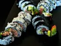Pyszne rolki sushi z tuńczykiem i awokado, posypane sezamem. Idealna rzepa do sushi na czarnej desce.