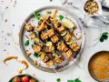 Pyszne szaszłyki z tofu satay, polane kremowym sosem orzechowym, z dodatkiem cukinii i limonki.