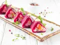 Roladki z buraka z farszem, przypominające sushi ze śledziem, ozdobione majonezem i ziołami.