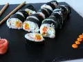 Rolka sushi philadelphia z łososiem, awokado i ogórkiem, podana z imbirem i wasabi.