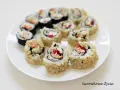 Pyszne rolki sushi, w tym kaburamaki, ułożone na białym talerzu.