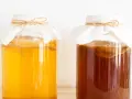 Dwa słoje z kombuchą, jeden jasnożółty, drugi ciemnobrązowy. Zastanawiasz się nad kombucha szkodliwość?