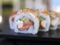 Uranaki z łososiem, kremowym serkiem i ogórkiem, zwieńczone krewetką. Pyszne danie sushi.