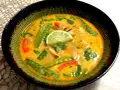 Aksamitna zupa tom kha z kurczakiem, z zielonym groszkiem, papryką i plasterkiem limonki.