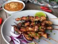 Aksamitny sos orzechowy dopełnia grillowane satay z kurczaka, podane z czerwoną cebulą i limonką.