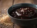 Gęsty, ciemny sos w misce, posypany sezamem. Obok garść ziaren sezamu. Idealny, gdy szukasz, czym zastąpić sos teriyaki.