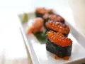 Pięć kawałków sushi z kawiorem, podanych na białym talerzu z odrobiną wasabi i marynowanego imbiru.