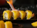 Płomień palnika opala sushi z mango, tworząc apetyczny wygląd.