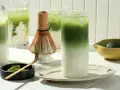 Zielone napoje matcha z lodem, bambusowa miotełka i proszek matcha.