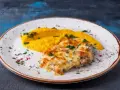 Pyszny katsu z kurczaka zapieczony z serem, podany z purée z dyni i posypany ziołami.