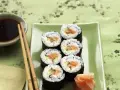 Sześć kawałków sushi z łososiem i ogórkiem, podanych z imbirem i sosem sojowym.