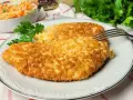 Dwa chrupiące kotlety z kurczaka w panko, podane na talerzu z sałatką z kapusty i marchewki.