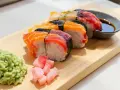 Kolorowe sushi z łososiem i tuńczykiem, podane z wasabi, marynowanym imbirem i sosem sojowym. Idealne sushi składniki na desce.