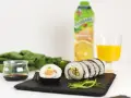 Roladki sushi z surowym łososiem do sushi, ogórkiem i ryżem, podane z sosem sojowym i sokiem pomarańczowym.