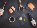 Słodki sos sojowy z butelki obok sushi z krewetkami i łososiem. Idealny dodatek do japońskich przysmaków.