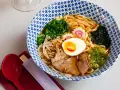 Miseczka aromatycznego makaronu ramen z jajkiem, mięsem, warzywami i kiełkami. Idealny posiłek, który dostarczy energii i zaspokoi głód.