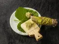 Świeży korzeń wasabi i starta pasta na deseczce. Czy wasabi jest ostre? Tak, jego ostrość jest intensywna i aromatyczna.