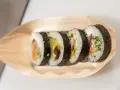 Pięć kawałków sushi z łososiem, awokado i krewetkami na drewnianej łódce. Różne rodzaje sushi nazwy.