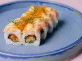 Roladki sushi z łososiem i chrupiącą posypką, z delikatnym akcentem, który przypominałby wasabi w ciąży, gdyby nie był to sos.
