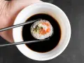 Pałeczkami zanurzam sushi z łososiem i kremowym nadzieniem w sosie sojowym. Idealny sojowy ser do sushi.