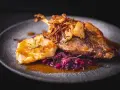 Pyszna kaczka po seczuańsku z chrupiącą cebulką, purée ziemniaczanym i czerwoną kapustą na kamiennym talerzu.