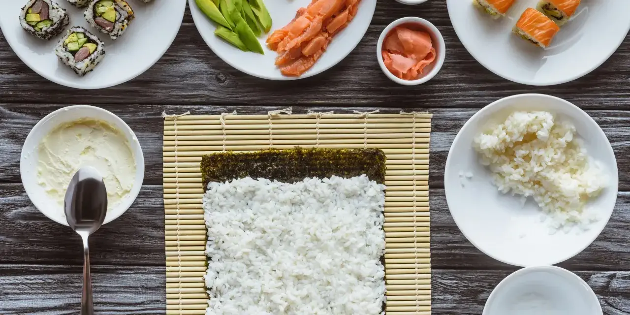 Idealny ryż do sushi jest kleisty i gotowy do zwinięcia z nori, łososiem i awokado.