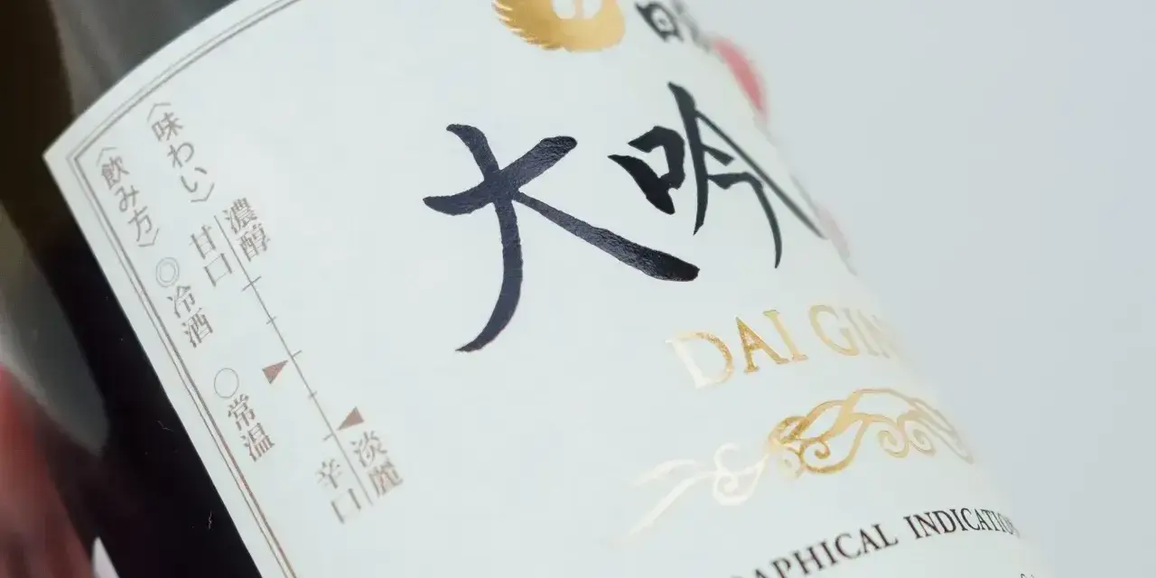 Butelka sake Dai Ginjo. Na etykiecie widnieje informacja o zawartości alkoholu, smakach i sposobie podania.