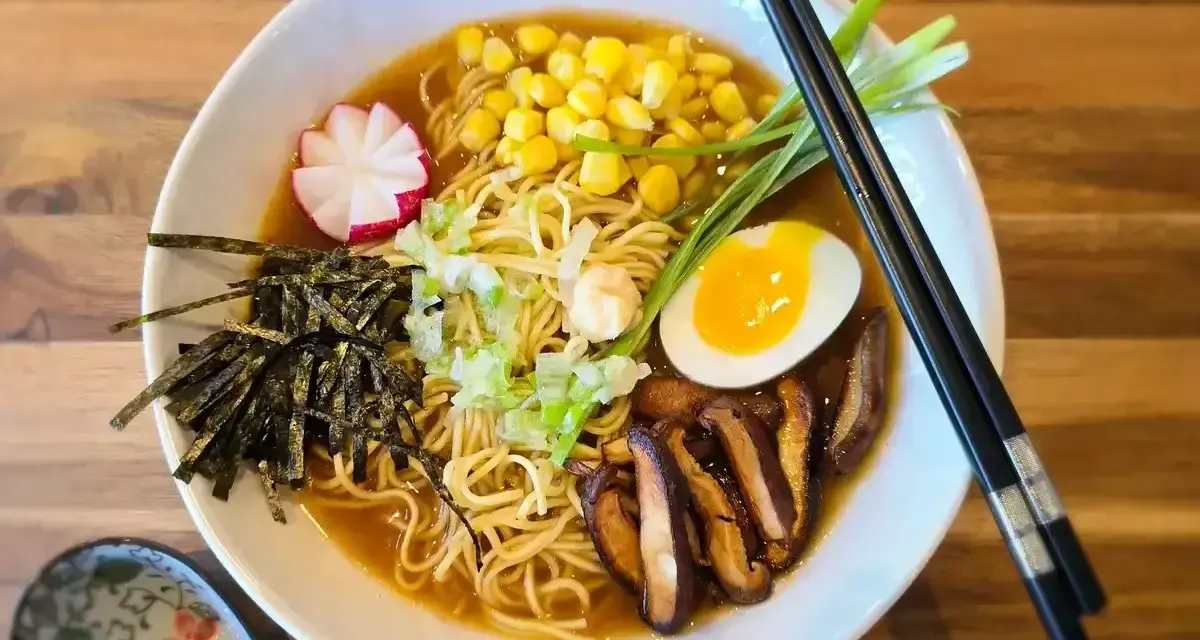 A miska pełna aromatycznego ramen miso z makaronem, jajkiem na pół, kukurydzą, grzybami shiitake, nori i szczypiorkiem.