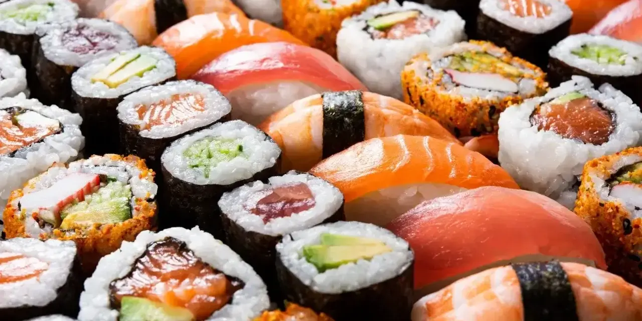 Różnorodne sushi, w tym rolki z łososiem i awokado, idealne dla dzieci. Czy dzieci mogą jeść sushi? Tak, jeśli wybierzemy łagodne składniki!