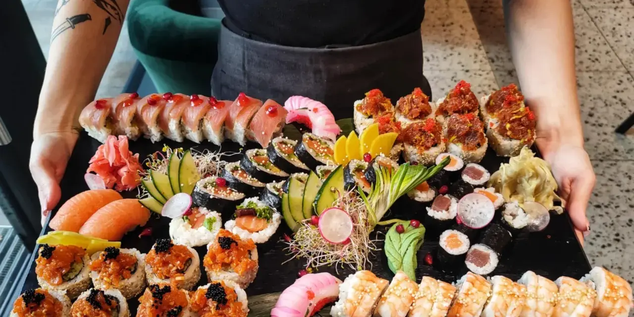 Taca pełna różnorodnego sushi: rolki z łososiem, tuńczykiem, krewetkami, a także nigiri. To właśnie sushi!