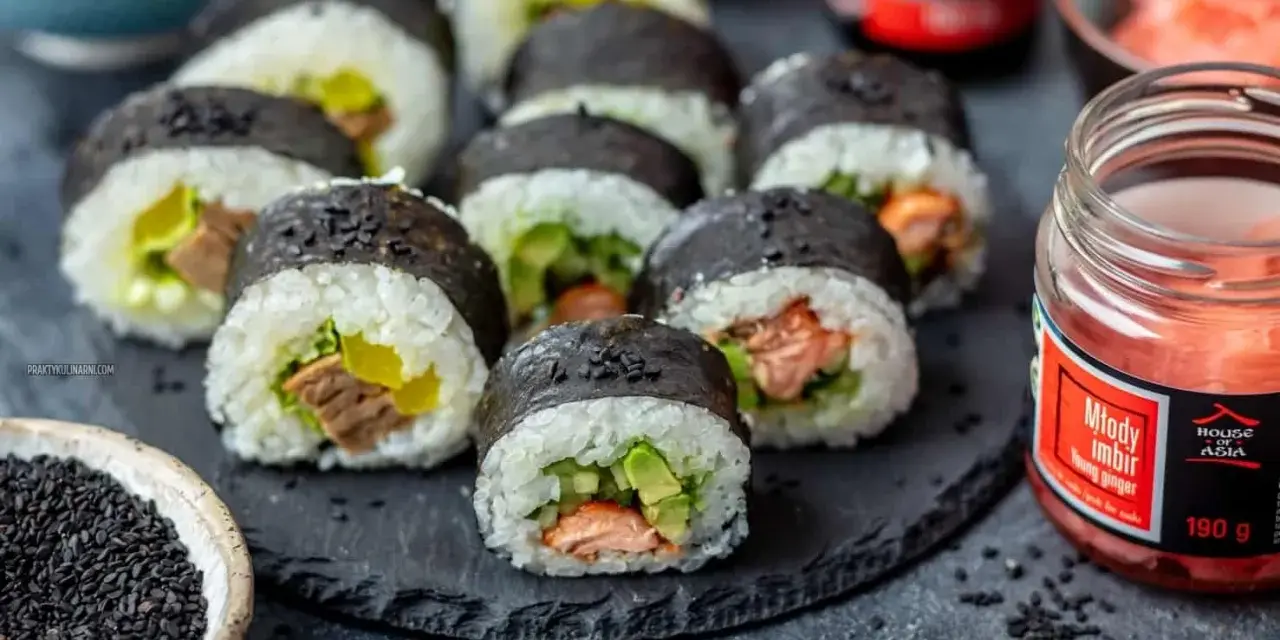 Pyszne sushi z łososiem, awokado i ogórkiem, posypane czarnym sezamem. Obok słoiczek marynowanego imbiru.
