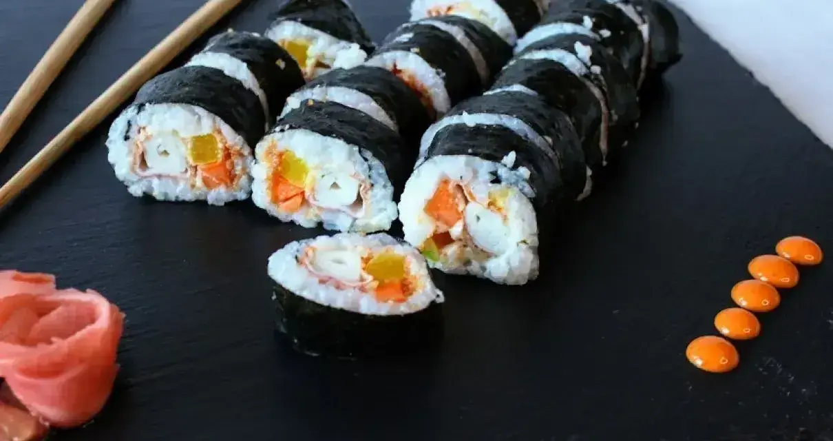 Rolka sushi philadelphia z łososiem, awokado i ogórkiem, podana z imbirem i wasabi.
