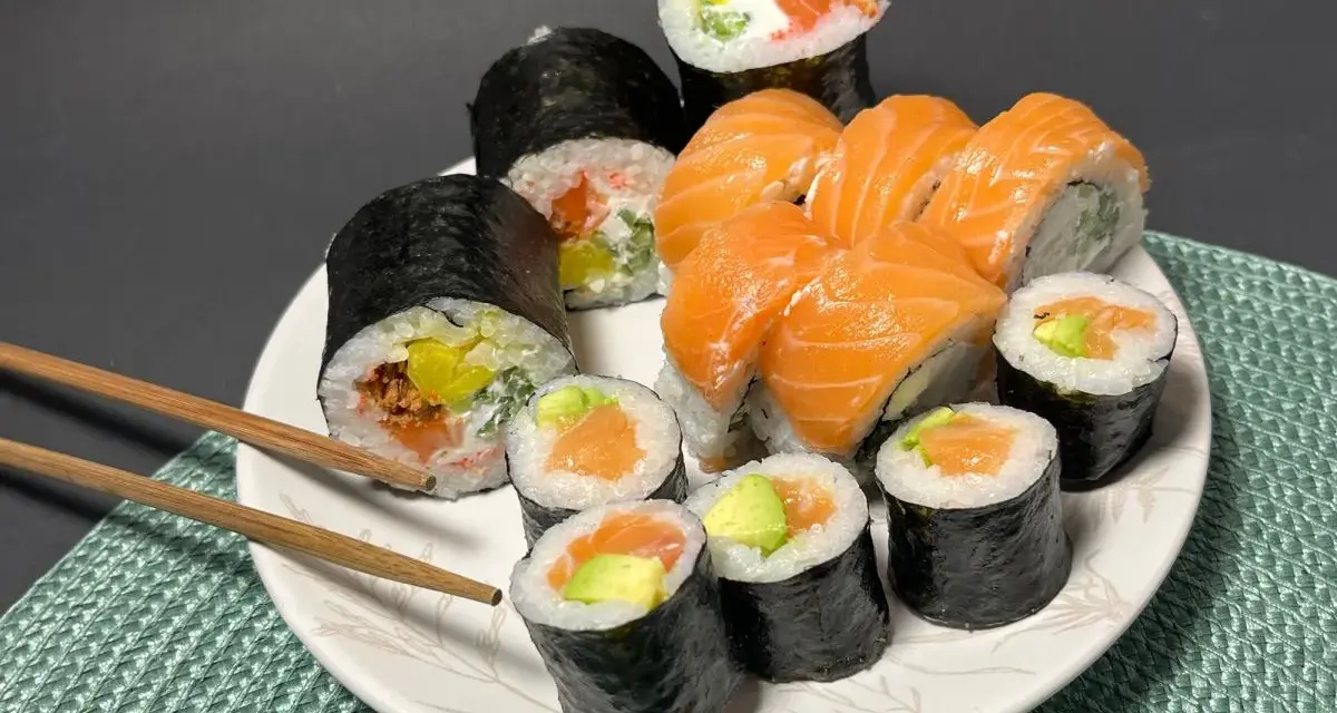 Talerz pełen sushi z łososiem i awokado. Wśród nich rolka z kremowym serkiem do sushi, idealna na przekąskę.