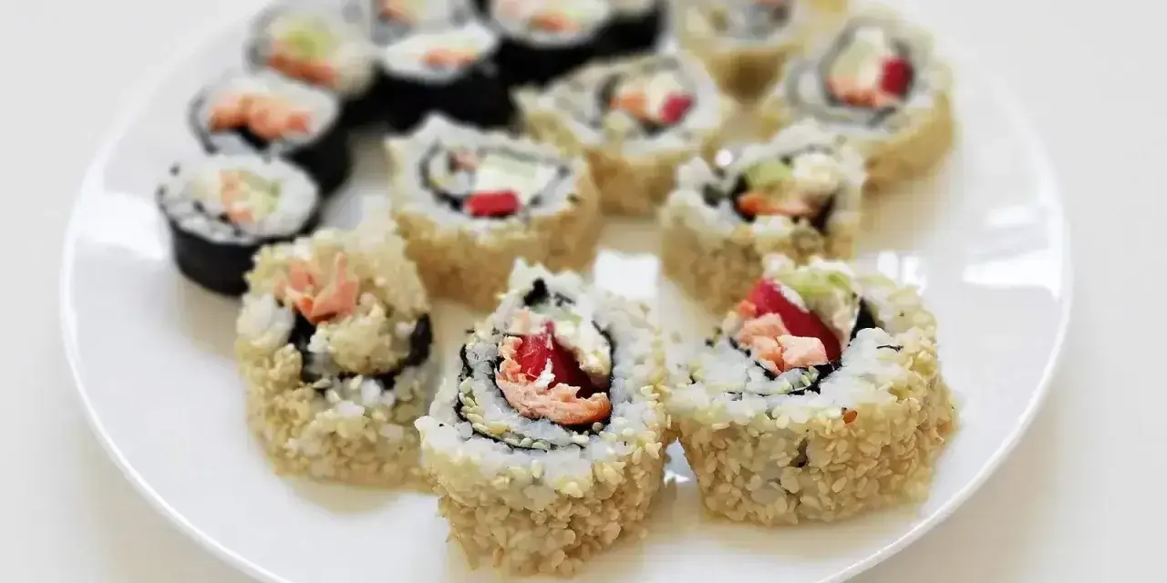 Pyszne rolki sushi, w tym kaburamaki, ułożone na białym talerzu.