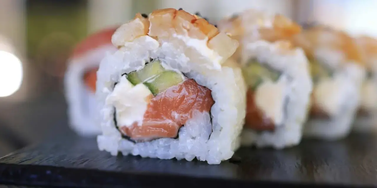 Uranaki z łososiem, kremowym serkiem i ogórkiem, zwieńczone krewetką. Pyszne danie sushi.