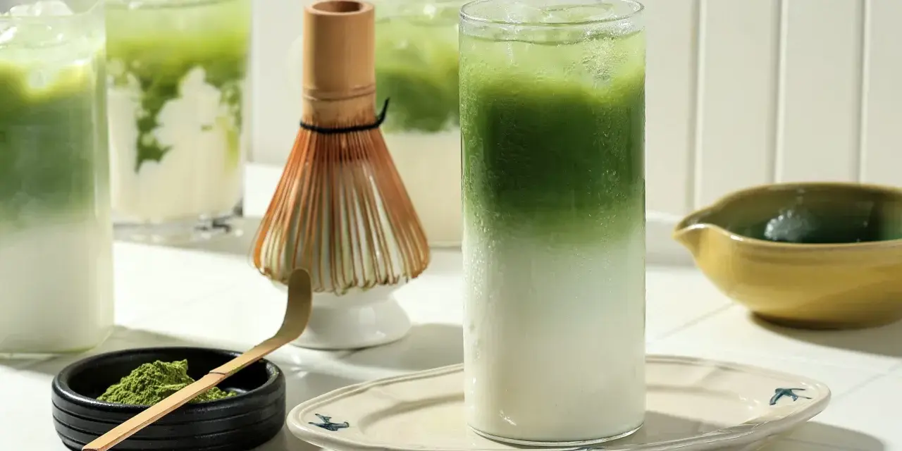 Zielone napoje matcha z lodem, bambusowa miotełka i proszek matcha.