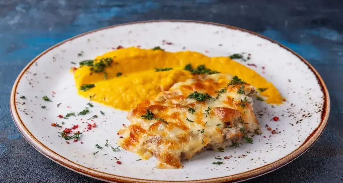 Pyszny katsu z kurczaka zapieczony z serem, podany z purée z dyni i posypany ziołami.