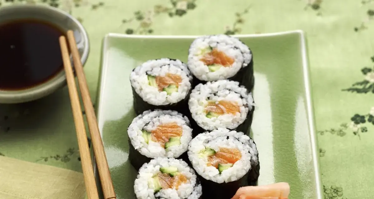 Sześć kawałków sushi z łososiem i ogórkiem, podanych z imbirem i sosem sojowym.