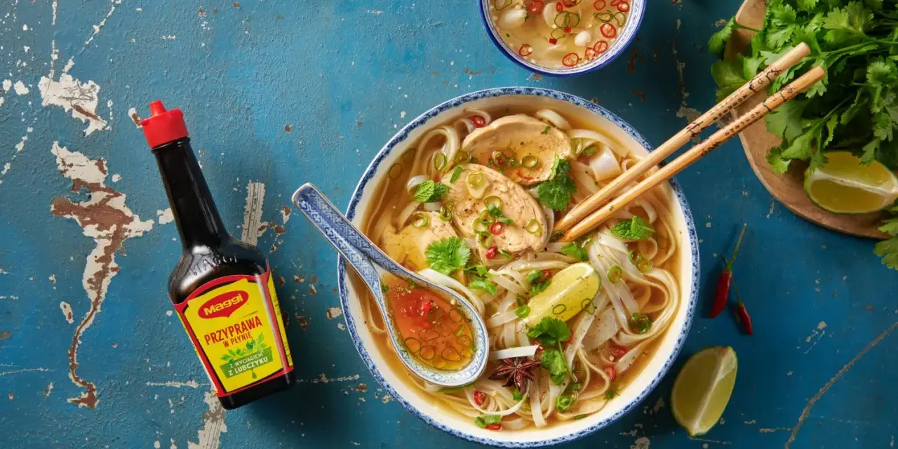 Aromatyczna zupa mien z kurczakiem, makaronem ryżowym, limonką i chili. Obok butelka przyprawy Maggi.