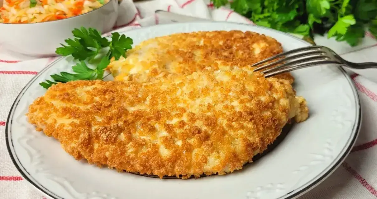 Dwa chrupiące kotlety z kurczaka w panko, podane na talerzu z sałatką z kapusty i marchewki.