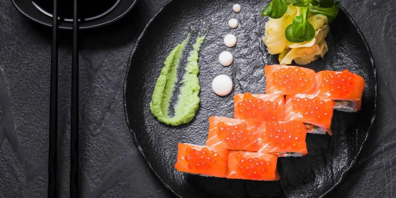 Roladki sushi z łososiem i ikrą, podane z zielonym, pikantnym wasabi prawdziwe, imbirem i sosem sojowym.